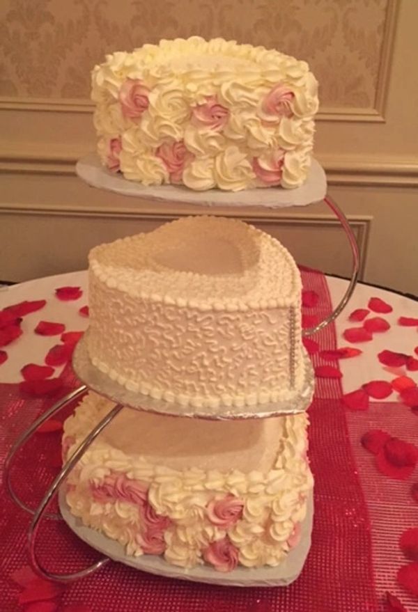 Heart shaped cake with pink and white buttercream swirls and white cornelli lace