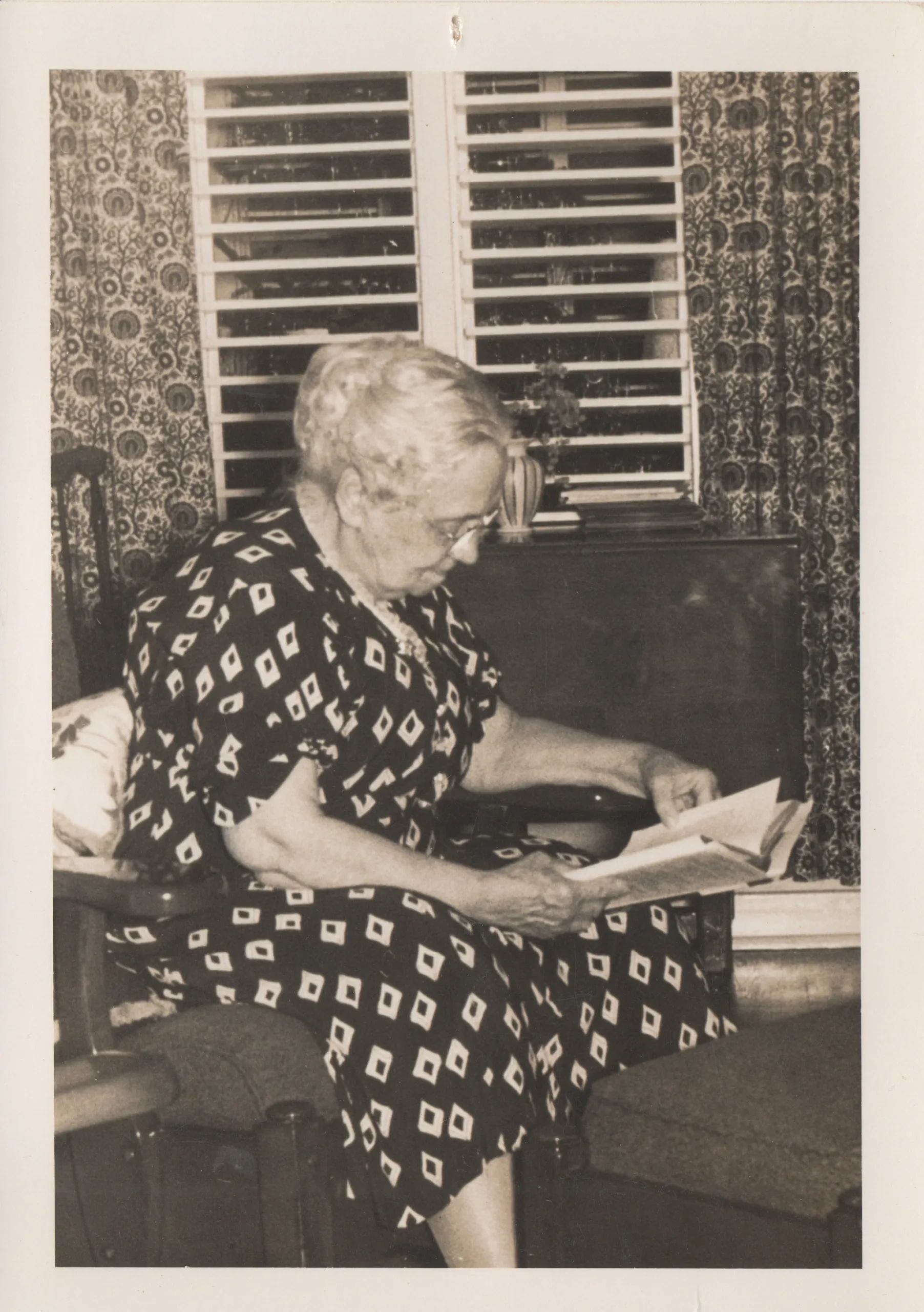 Black and white photo of older woman with white hair reading a book. (My great grandmother Della)
