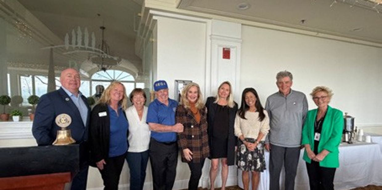 Group of nine people posing together indoors, some smiling.