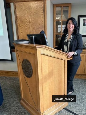 Woman standing at a wooden podium in a formal setting.