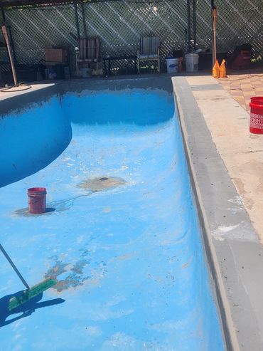 Empty pool being cleaned with broom and buckets around.