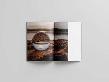 Open book showing a crystal ball on sandy terrain near water.