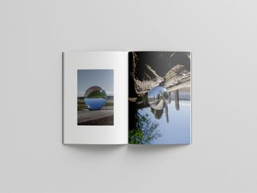 Open book showing photos of crystal balls reflecting landscapes.