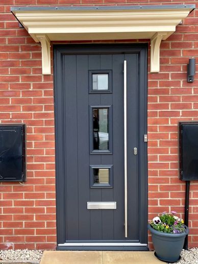 Modern dark gray front door with three small windows and a metal handle.