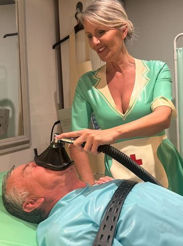 Patient and Mistress in medal play wearing latex medical outfits.