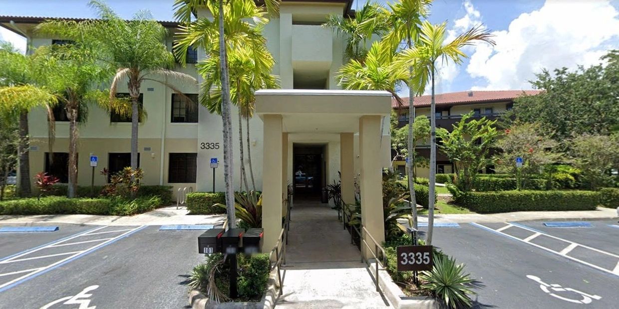 Entrance to a residential building with address 3335 and palm trees.