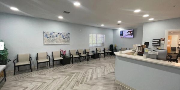 Modern waiting room with chairs, TV, and reception desk.