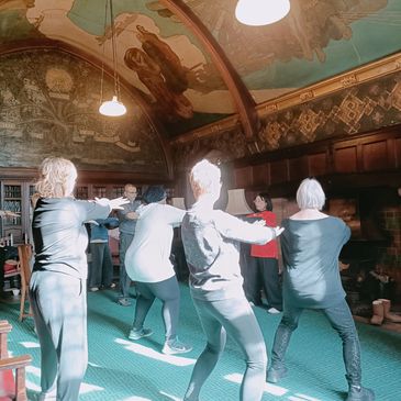 Former IW TaiChi Classes for adults with chronic conditions. People standing doing TaiChi.