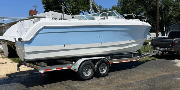 Light blue and white boat on a trailer hitched to a pickup truck.