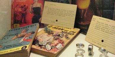 Cufflinks sitting on pulp crime novels by Peter Cheyney rings in front of a book about coffee