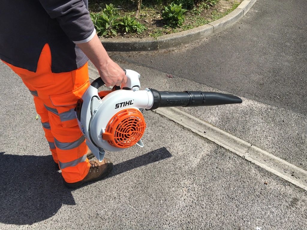 Grounds maintenance operative using a leaf blower