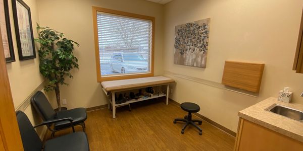 Image of a patient room. All are large with a sink, hard wood floors and a medical bench