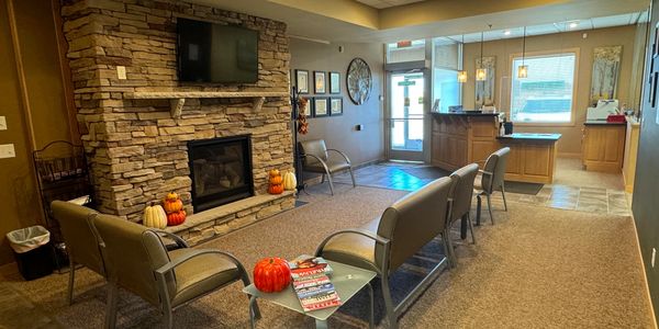 Image of the lobby, complete with a front desk, chairs and a fireplace.