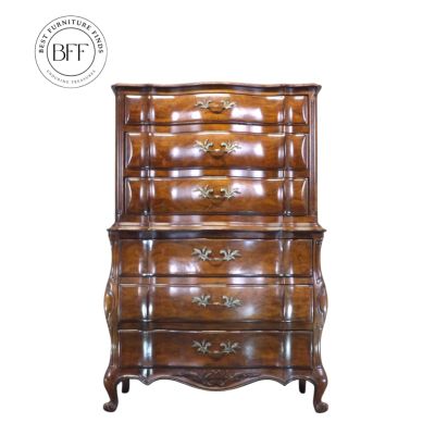 Elegant vintage wooden dresser with ornate handles and curved design.