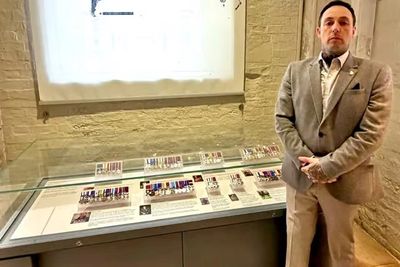Andrew (Andy) Radford CGC standing beside The Household Cavalry Museum display of gallantry medals.