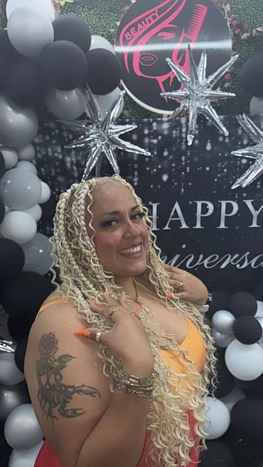 Woman with blonde braided hair and tattoos smiling at a celebration.