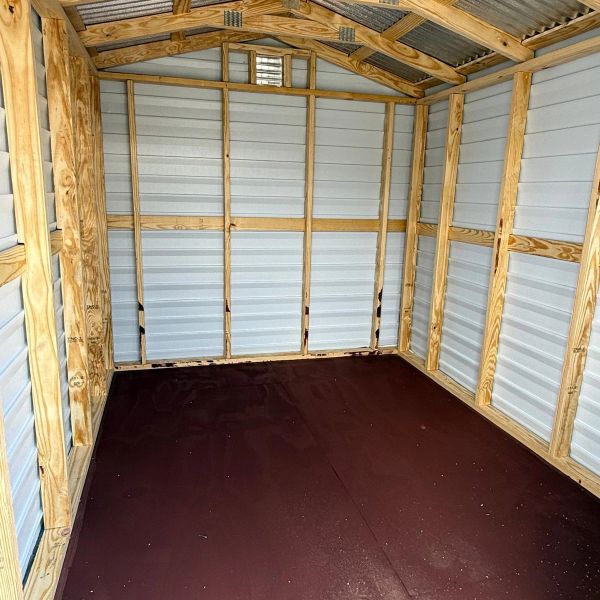Empty wooden and metal shed interior with brown floor.