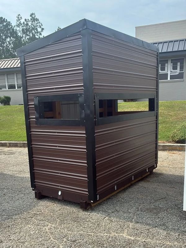 A small brown metal shed with windows on its side.