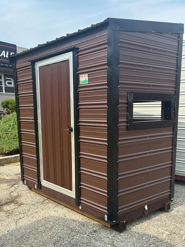 Small brown metal shed with a door and a side window opening.
