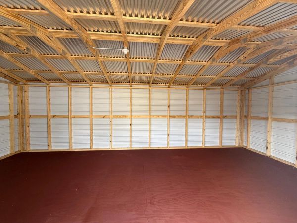 Empty room with wooden framing and corrugated metal walls and ceiling.