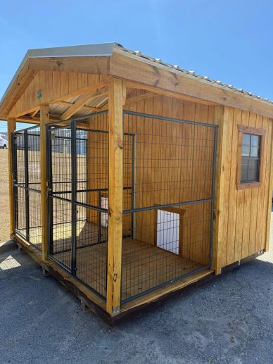 Wooden dog kennel with metal fencing and small dog door.