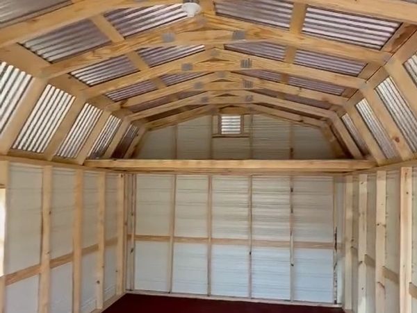Interior of a wooden and metal shed with a pitched roof and exposed beams.