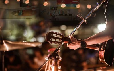 Entertainer on stage holding a guitar in Kona Tap Room