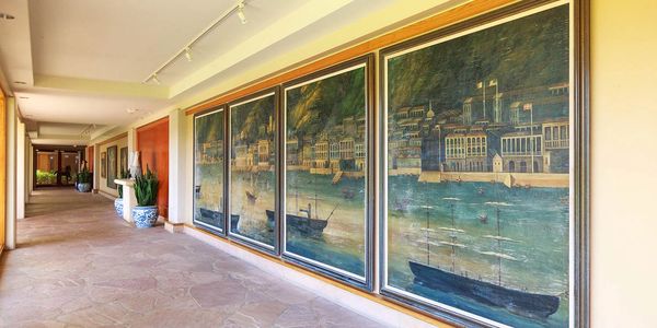 Museum walkway at the resort with large paintings on the right side of the wall area.