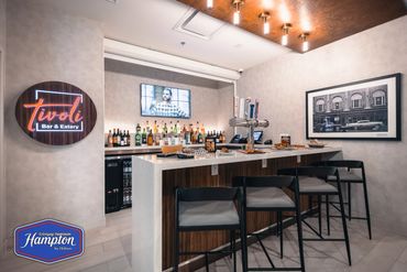 Modern bar interior with neon sign and seating at the counter.