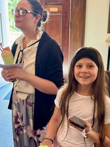 Smiling girl with braces and woman holding papers indoors.