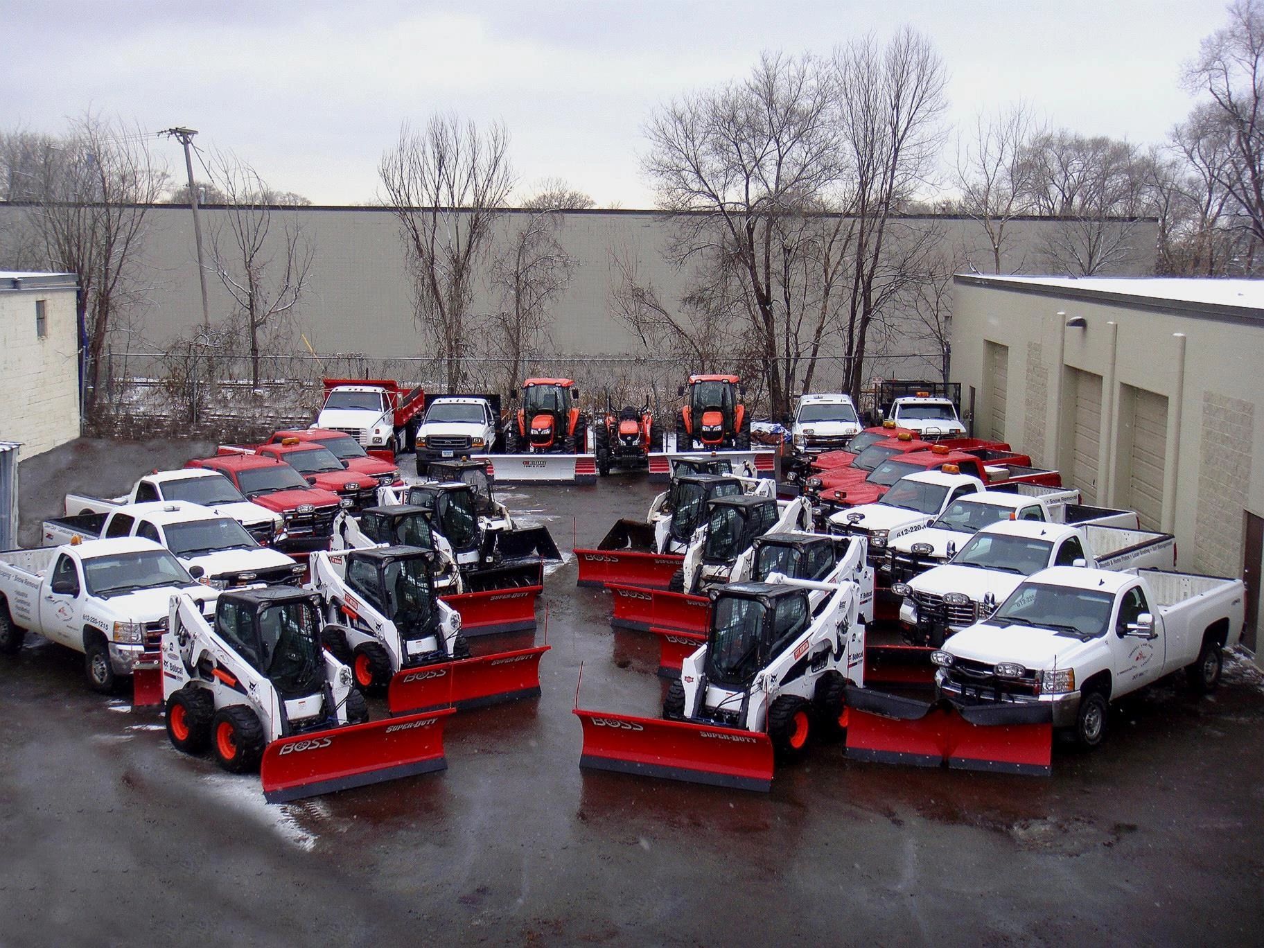 Trucks, tractors, and skid loaders equipped with plows and clear company branding
