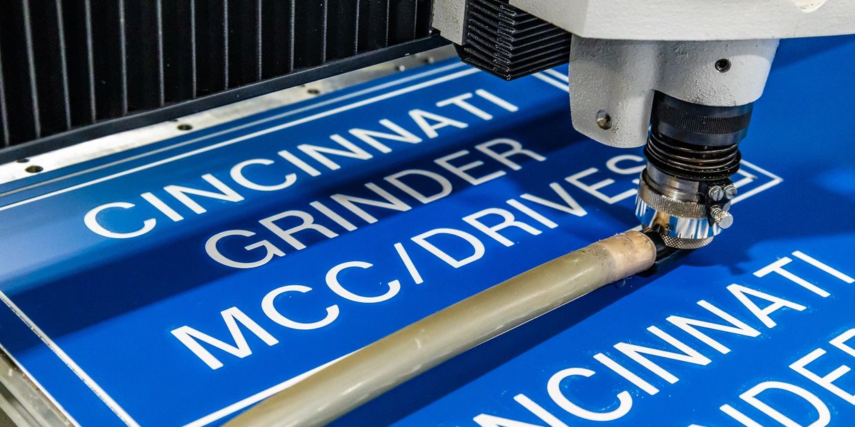 Royal blue acrylic asset signage being custom cut and engraved at Industrial Engravers.