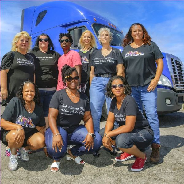Caption: a group of women standing next to each other in front of a blue truck