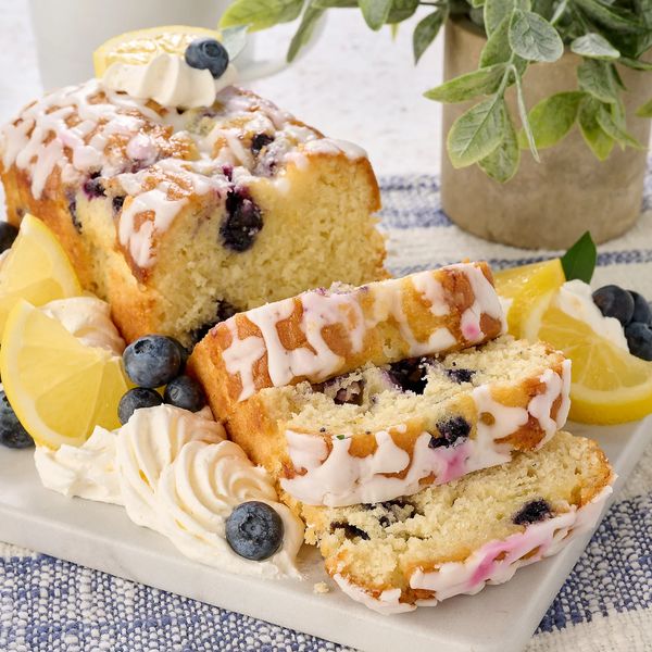 Blueberry lemon cake with icing and whipped cream garnished with fresh blueberries and lemon slices.
