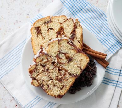 Two slices of cinnamon swirl bread on a white plate with cinnamon sticks.
