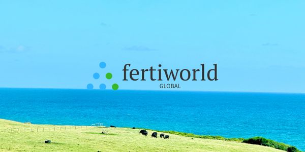 Green pasture with cows near a blue ocean under a clear sky.