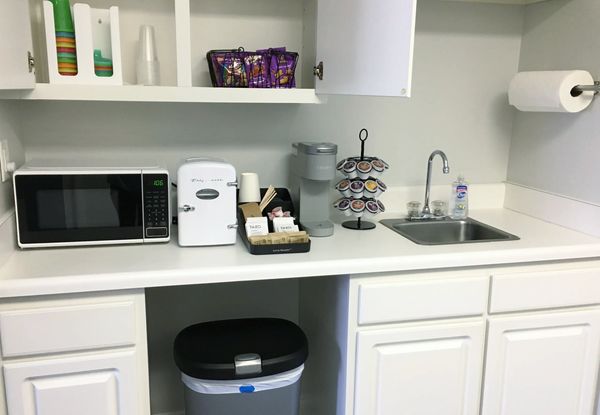 Kitchenette with small microwave, mini cooler with juice and water, Keurig, coffee, tea, snacks