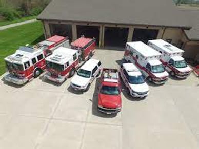 Emergency vehicles including fire trucks and ambulances parked outside a station.
