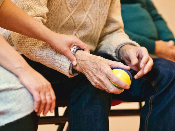 Mature woman in aged care facility receiving help from hospital staff nurse.
