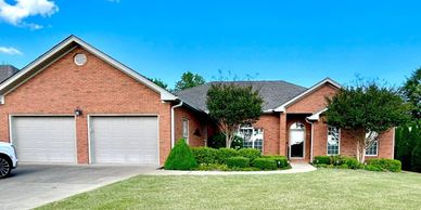 A single-story brick house with a two-car garage and manicured front yard.
