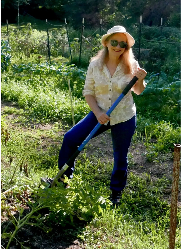 Mary T'Kach holding a spade in a potato field. 
