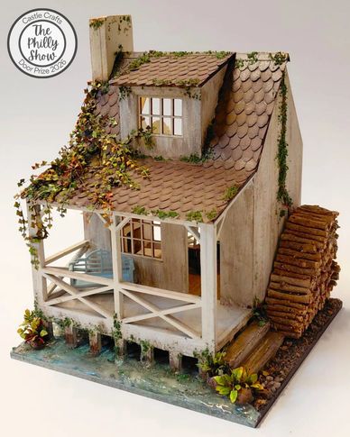 Miniature rustic watermill model with ivy and porch.