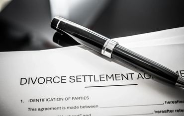 Close-up of a divorce settlement agreement with a black pen on top.