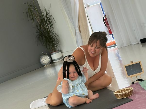 Mother and baby playing indoors with a spider hat.
