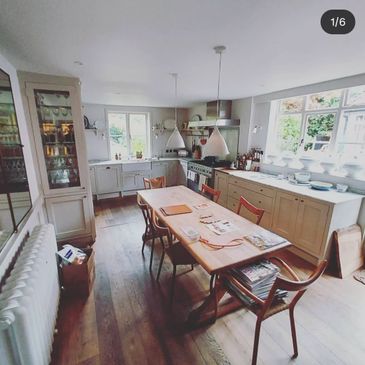 Bright and cozy kitchen with wooden floors and a central dining table.