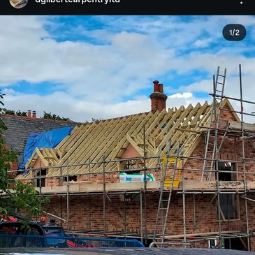 Brick house under roof construction with scaffolding and ladders.