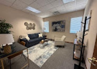 Cozy office lounge with seating, decor, and a presentation screen.
