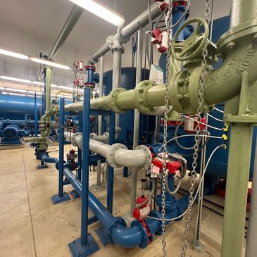 Industrial pipes and valves in a mechanical room.