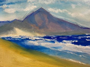 A serene beach scene with waves and a mountain backdrop.