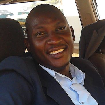 Man smiling inside a car wearing a suit.